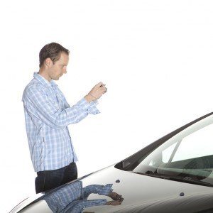 man taking a photo of a car with his camera phone