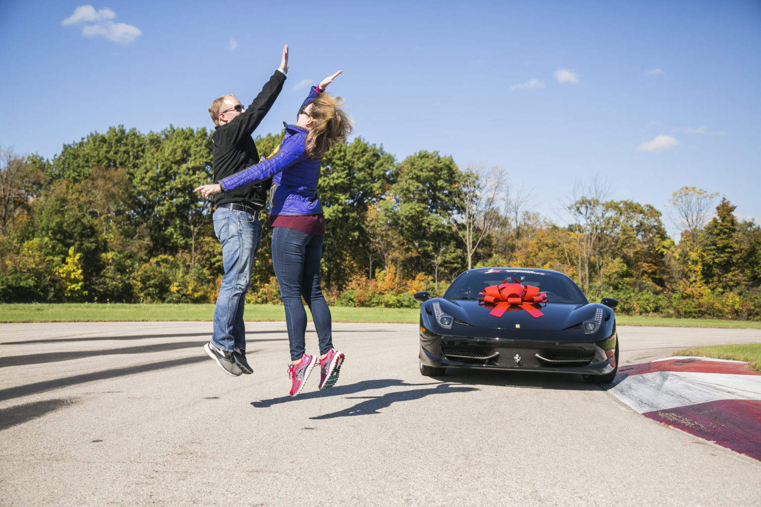 couple high five at track in front of black ferrari