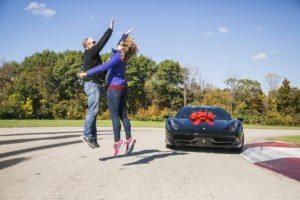 couple high five at track in front of black ferrari