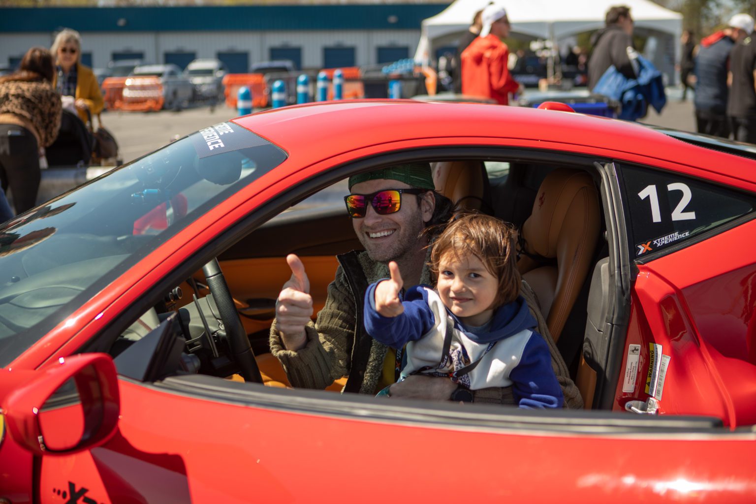 Father and son giving a thumbs up in the driver's seat of a supercar